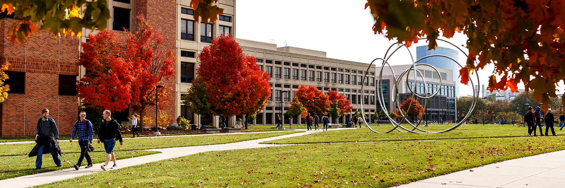 Students walk past vivid autumn trees on the IUPUI campus.